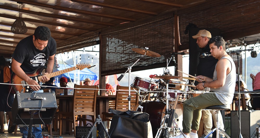 Una banda ajusta sus instrumentos y equipos previo a amenizar con música viva en un restaurante local.